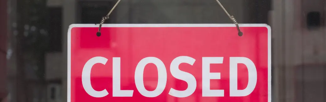 panneau rouge « CLOSED » accroché derrière une vitre